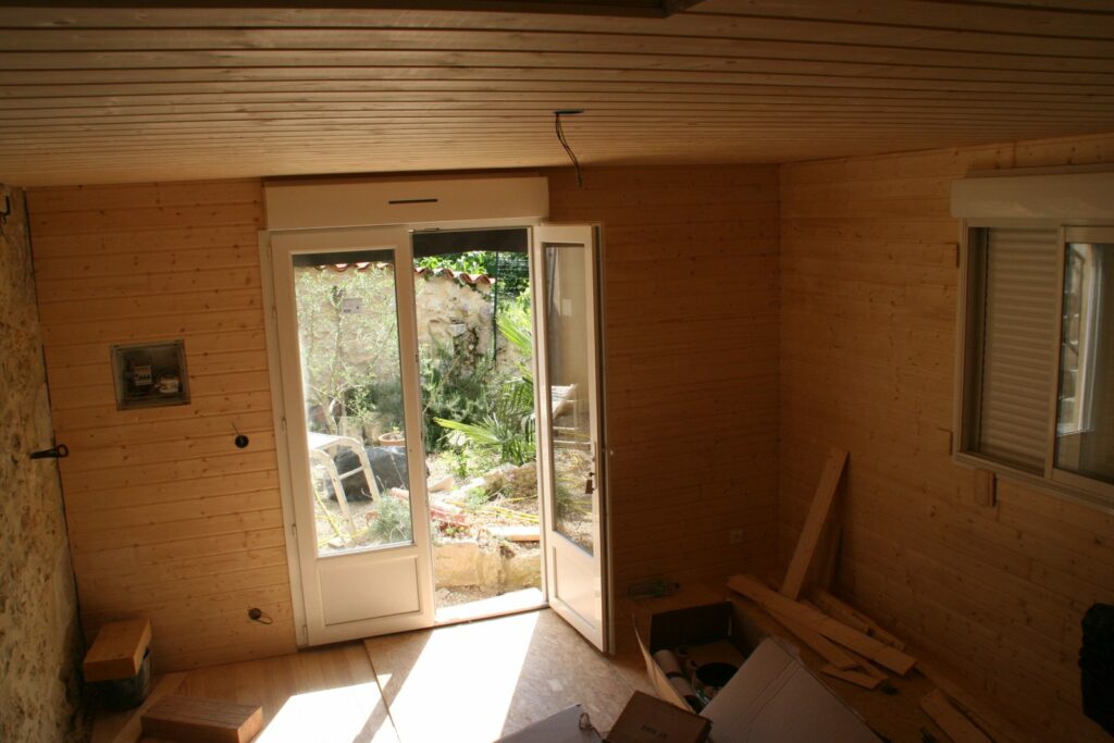 Rez-de-chaussée lambrissé, porte-fenêtre ouverte sur le jardin