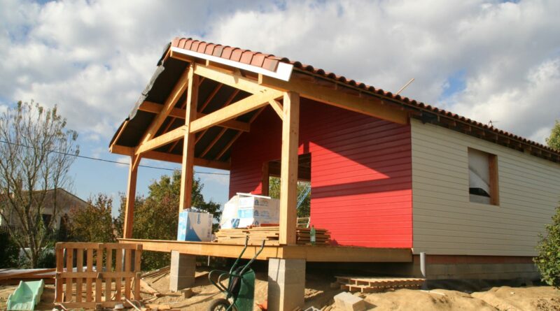Extension ossature bois avec terrasse couverte et bardage rouge