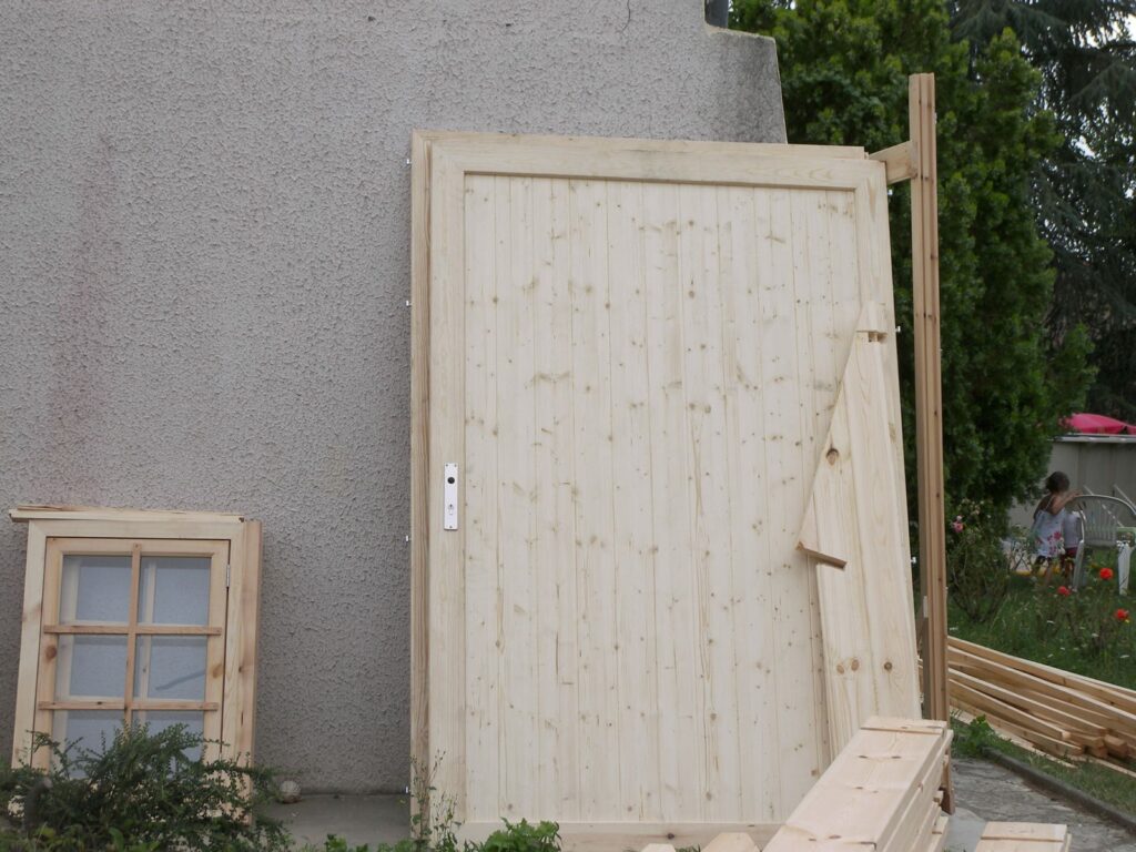 Porte de garage en bois et fenêtre posées contre un mur