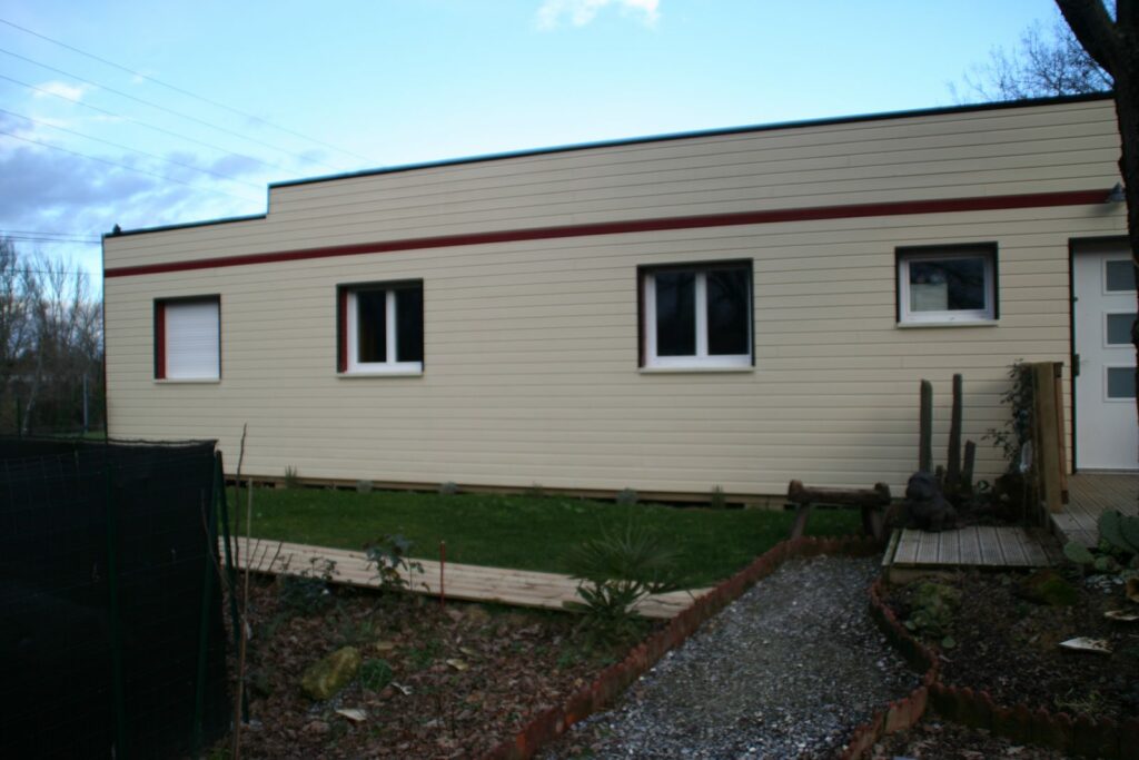 Façade de la maison bois en bardage ivoire avec bande rouge
