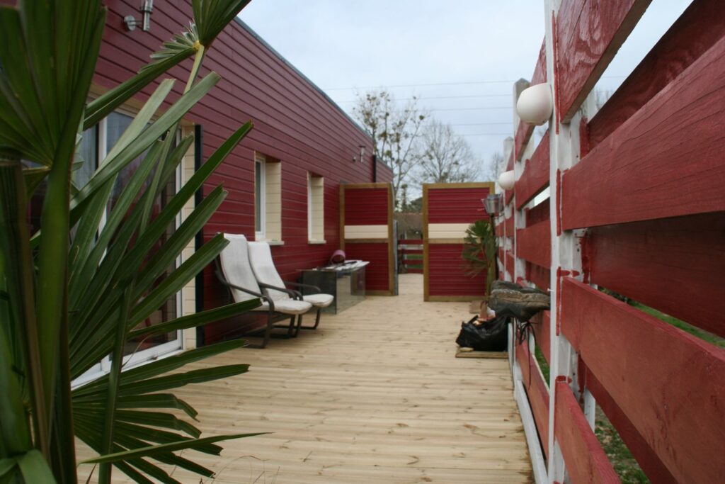 Terrasse en bois le long du bardage rouge de la maison